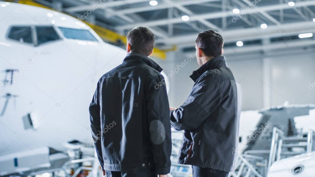 Aircraft Maintenance Workers having Conversation. Holding and using Tablet.