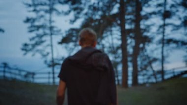 Avrupa Çam Ormanı'nda Uçurumun Kenarına Doğru Yürüyen Genç Adam. Deniz Onun Önündedir. Tişört giyiyor. Alacakaranlık Saatinde Doğada Sıcak Bir Akşam. Arkadan Vuruldu.