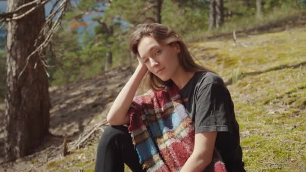 Retrato de uma jovem bela morena em uma atmosfera romântica da manhã com em um acampamento ou uma floresta. Ela expressa um sorriso bonito. Natureza e floresta de pinheiro estão no fundo. Quente dia ensolarado . — Vídeo de Stock