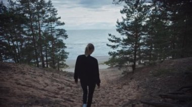 Romantik Bir Doğa Atmosferinde Genç Güzel Sarışın Kadının Portresi. Kız Siyah giyinmiş ve Plaj ve Deniz için bir Sandy Path Aşağı Yürüyor. Ormanda Tek Başına Yürüyor.