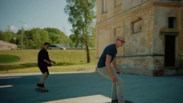 Двоє крутих молодих хлопців катаються на дошці та скейтборді через стильну культурну частину міста. Скейтбординг в постіндустріальному районі. Повільний рух після пострілу — стокове відео