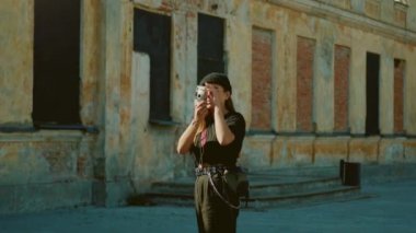 Cool Looking Arty Genç Kız Wearin Beanie ve Yuvarlak Gözlük Hipster City Mahallesi'nde Fotoğraf Çekmek için Film Kamera kullanır. Şık Esmer Teen Fotoğraflar Kültürel Hip Binalar
