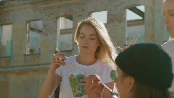 Şehrin Şık Hipster Bölümünde Bankta Otururken Güzel Kızlar Yeme Take Away Sokak Gıda. Parkta Sağlıklı Gıdalar Yeme Üç Mutlu Girlfriends — Stok video