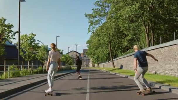 Coole junge Mädchen und zwei Jungs, die auf Longboards und Skateboards durch den hippen kulturellen Teil der Stadt fahren. Skateboarding auf der Straße im Hipster-Viertel. Nach Zeitlupenkamerafahrt — Stockvideo