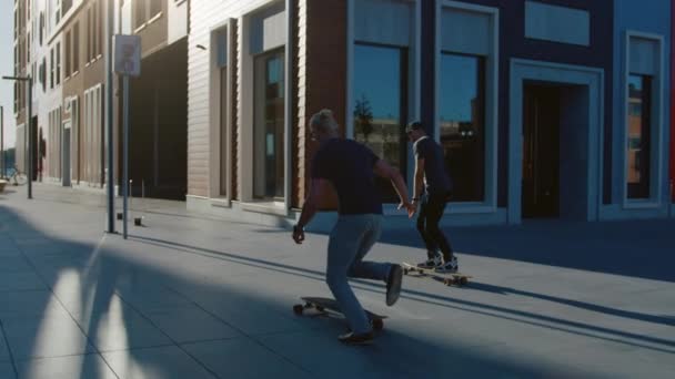Two Professional Skaters Riding on Skateboards Through Fashionable Hipster District. Handsome Guy Skateboarding Through Modern City Street. Following Slow Motion Camera Shot — Stock Footage Two Professional Skaters Riding on Skateboards Through Fashionable Hipster District. Handsome Guy Skateboarding Through Modern City Street. Following Slow Motion Camera Shot Stock Footage