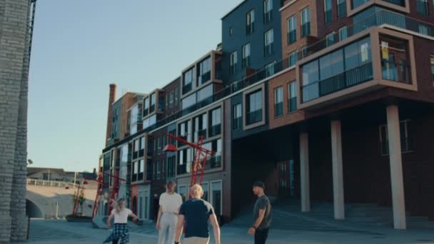 Csoport lányok és fiúk lovaglás Skateboards a divatos csípő kerületi. Gyönyörű fiatalok gördeszka keresztül modern City Street. Alábbiak lassú jelet ad fényképezőgép szemcsésedik — Stock videók