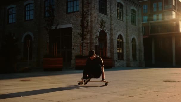 Atletische professionele skater staat op de handen op zijn skateboard. Sterke kerel doet handstand trucs op een Longboard. Op de achtergrond modieuze hipster City district Street — Stockvideo