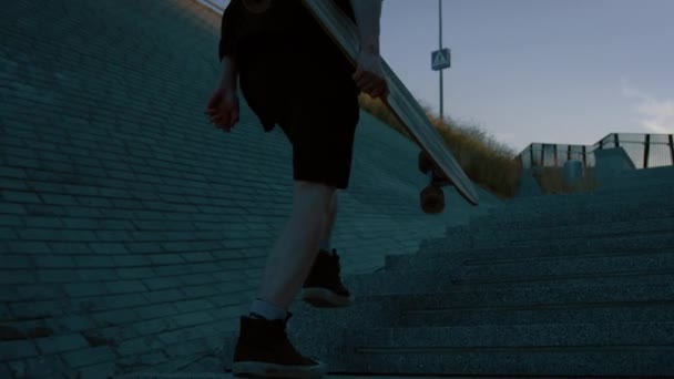 Efter skott av den unge mannen kör uppför trappan medan du bär skateboard. I bakgrunden fashionabla moderna hipster District — Stockvideo