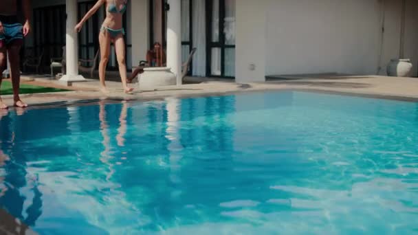 Schöne blonde Mädchen und schöner athletischer Junge tauchen kopfüber in den Pool. Attraktive junge Leute springen ins blaue Wasser des Freibades, um sich abzukühlen. Schönes Sommerferienkonzept — Stockvideo
