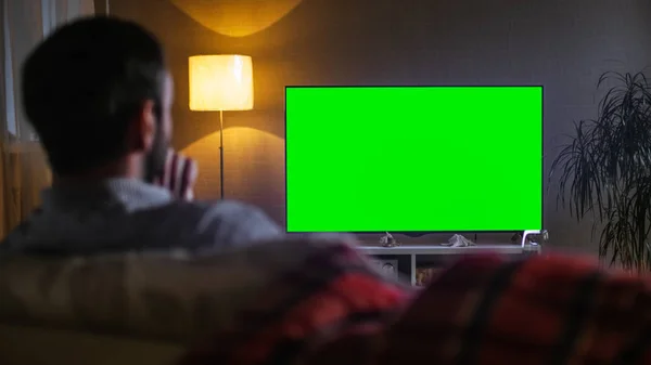 La sera indietro Vista di un uomo di mezza età seduto su un divano a guardare una grande TV a schermo piatto . — Foto Stock