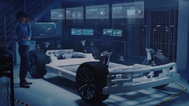Μηχανικός σετ κεφαλής επαυξημένης πραγματικότητας επιλέγει σώμα για την ιδέα του νέου ηλεκτρικού αυτοκινήτου. Απεικόνιση γραφικών 3D δείχνει το πλαίσιο του οχήματος να αναπτύσσεται σε πραγματικό χρόνο σε ρεαλιστική έννοια — Αρχείο Βίντεο