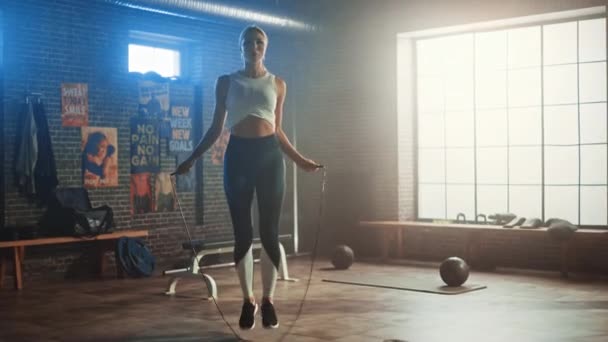 Fit Athletic Blond Woman Exercícios com Jumping Rope em um Ginásio Industrial Estilo Loft. Ela faz seu intenso programa de treinamento de aptidão cruzada. As instalações têm cartazes motivacionais na parede. Movimento lento . — Vídeo de Stock