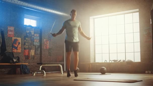 Mužský atletický mladý muž cvičení s skákací lanem ve stylu podkroví průmyslová tělocvična. Dělá si program pro intenzivní cross-fitness výcvik. Facilita má motivační plakáty na stěně. — Stock video