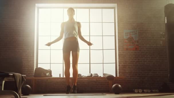 Ejercicios fuertes de la mujer atlética con la cuerda que salta en un gimnasio industrial del estilo Loft. Está concentrada en su intenso programa de entrenamiento físico. Ventana grande detrás de ella . — Vídeos de Stock