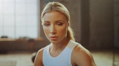 Motivasyon posterleri ile Bir Loft Sanayi Spor Salonu'nda Oturan Güzel Güçlü Fit Blond Portresi. Yoğun Fitness Eğitim Programı'ndan sonra Nefesini Tutuyor. Yakın Çekimde Gösterilen Atlet Yüzü.