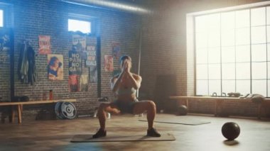 Strong and Fit Beautiful Athletic Woman in Sport Top ve Shorts is doing Squat Exercises in a Loft Style Industrial Gym with Motivational Posters. Cross Fitness Antrenmanının bir parçası..