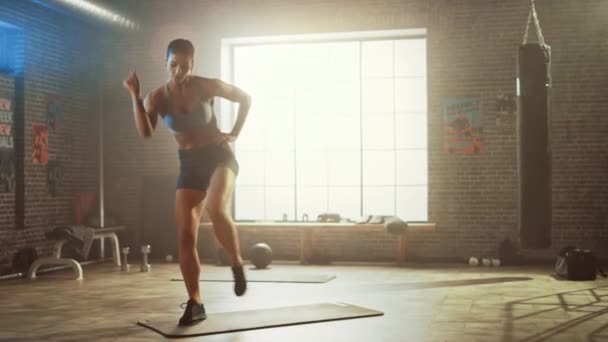 Silná a fit krásná atletická žena ve sportu Top a šortky má stálý březen cvičení ve stylu podkroví průmyslová tělocvična s motivačními plakáty. To je tréninkový trénink.