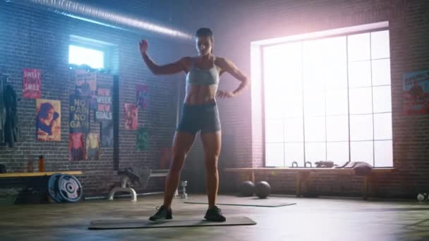 Sterk en fit mooie atletische vrouw in sport top en shorts doet maart en twist oefeningen in een loft-stijl industriële Gym met motiverende posters. Het is haar cross Fitness Training workout. — Stockvideo