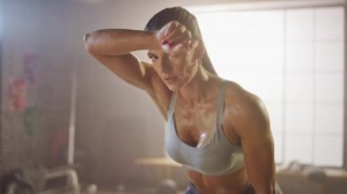 Motivasyonposterler ile Bir Loft Sanayi Spor Salonu'nda Yüzünde Bir Güzel Güçlü Fit Esmer Silme Sweat Portresi. O Yoğun Fitness Eğitim Egzersiz sonra Onu Nefes Catching's. Sıcak Işık.