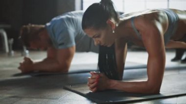 Güçlü Erkeksi Adam ve İki Fit Atletik Kadın Çekirdek Güçlerini Çalışmak İçin Plank Pozisyonunda Dururlar. Sarışın Kız bitkin ve eğitimle boğuşuyor. Çatı katında spor yapıyorlar..