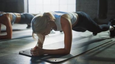 Güçlü Erkek ve İki Fit Atletic Kadınlar Onların Çekirdek Gücü Egzersiz Için Bir Tahta Pozisyon Tutun. Adam Yorgun ve Eğitim ile mücadele ediyor. Onlar Bir Loft Spor Salonunda Egzersiz.