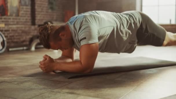 Sterke mannelijke en twee fit atletic vrouwen houden een plank positie om hun kernkracht uit te oefenen. De mens is uitgeput en worstelt met trainingen. Ze trainen in een loft Gym. — Stockvideo