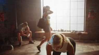 Beautiful Fit Athletic Blond Kadın Yerden bir Barbell Kaldırma ve Her Günlük Fitness Eğitim Rutin olarak Geri Güçlendirme Egzersiz yapıyor. Loft Spor Salonu'nda Sportif İnsanlarla Çalışıyor.