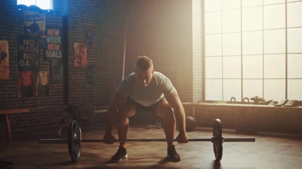 Ο όμορφος μυώδης Man κάνει την εναέρια ανύψωση με ένα barbell σε ένα μικρό αυθεντικό γυμναστήριο. Αθλητικός άνθρωπος εκπαίδευση το μπράτσο του μύες και ασκήσεις με barbell. Προπόνηση στο hardcore γυμναστήριο. Θερμό φως. — Αρχείο Βίντεο