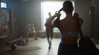 Hardcore Spor Salonu'na Güzel Atletik Womanwalking Shot ardından, Onun Arkadaşlar ve Diğer Sporcular Selamlıyor. Onun Güç Egzersiz, Güç Egzersiz ve Vücut Geliştirme Eğitim Oturumu için hazır