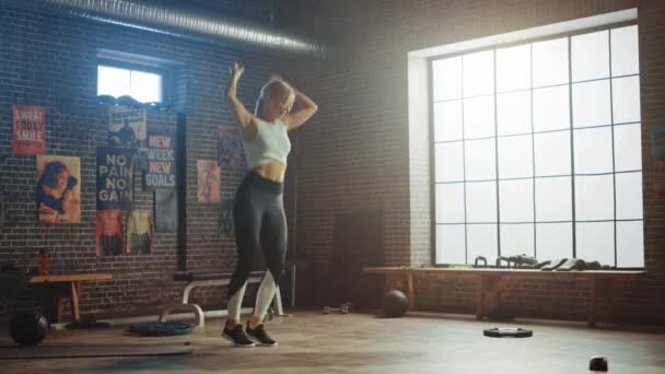 Porträtt av Super Happy Athletic blond tjej hoppar, dansar och firar sin framgång i utbildning, motion, träning, vikt, styrka, muskel-och kroppsfett mål resultat i Hardcore gym — Stockvideo