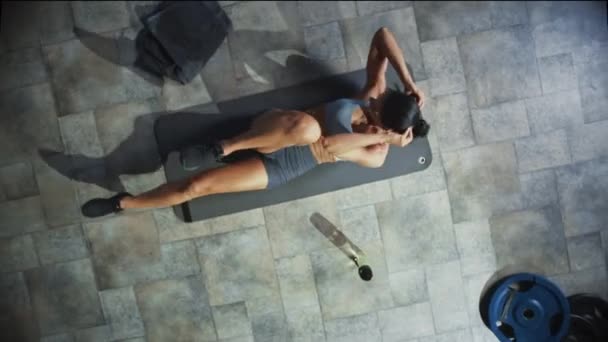 Vista dall'alto del culturista professionista che fa le crocchette della bicicletta mentre si sdraia sul tappetino da yoga nella palestra Hardcore. Muscolare e Atletica Bella Donna Muscolo, Potenza e Cardio Allenamento. Zoom Out — Video Stock