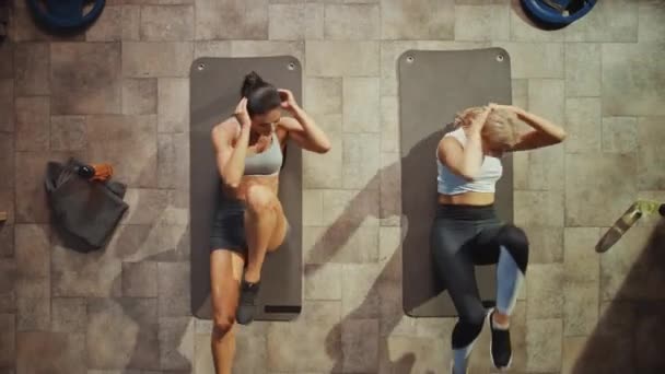 Widok z góry dwóch profesjonalnych kobiet kulturystów robi rower crunches leżąc na maty do jogi w Hardcore Gym. Muskularne i sportowe piękne dziewczyny mięśni, moc i Cardio Workout. Pomniejsz — Wideo stockowe