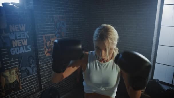 职业女子拳手在铁杆健身房穿着运动服和格斗手套时，练习踢和冲空的肖像。强大的美丽女孩拳击和自卫锻炼 — 图库视频影像