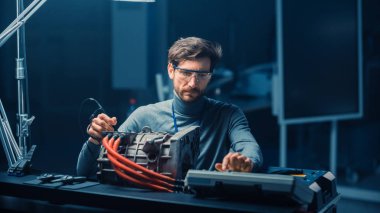 Bilgisayar ve Denetim Araçları ile Gözlük Profesyonel Otomotiv Mühendisi Bir Konsept Otomobil Şasi ile Yüksek Teknoloji Laboratuvarında Kullanılmış Elektrikli Motor Test.