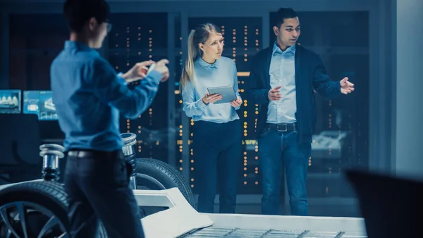 Shot of a Development Laboratory Room with Diverse Professional Team of Engineers and Scientists Trabajando en un Chasis de Coche Eléctrico con Ruedas, Baterías, Motor y Suspensión . —  Fotos de Stock