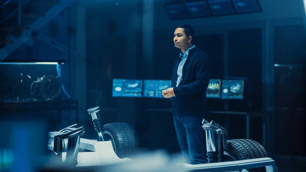 Ingeniero de diseño de automóviles en las instalaciones de innovación automotriz y trabajando en el prototipo de chasis de plataforma de coche eléctrico que incluye ruedas, suspensión, motor híbrido y batería . — Foto de Stock