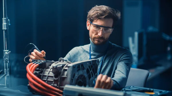 コンピュータと検査ツールを備えたメガネの専門の自動車エンジニアは、コンセプトカーシャーシを持つハイテクラボで中古電気エンジンをテストしています. — ストック写真