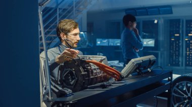 Bilgisayar ve Denetim Araçları ile Gözlük Profesyonel Otomotiv Mühendisi Bir Konsept Otomobil Şasi ile Yüksek Teknoloji Laboratuvarında Kullanılmış Elektrikli Motor Test.