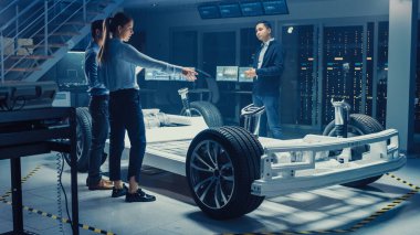 Otomotiv Tasarım Mühendisleri Elektrikli Araç Şasi Prototipi Üzerinde Çalışırken Konuşuyor. Yenilik Laboratuvarı Nda Tesis Konsept Araç Çerçevesi Tekerlekler, Süspansiyon, Motor ve Akü.