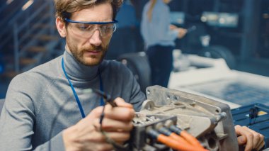 Bilgisayar ve Denetim Araçları ile Gözlük Profesyonel Otomotiv Mühendisi Bir Konsept Otomobil Şasi ile Yüksek Teknoloji Laboratuvarında Kullanılmış Elektrikli Motor Test.