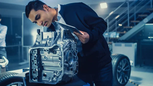 Development Laboratory Room with Professional Automotive Design Engineer Working on a Electric Car Gear Transmission. Chassis with Wheels, Batteries, Engine and Suspension.