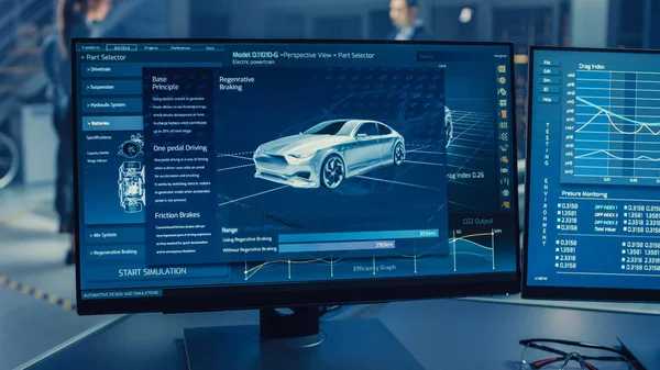 Professionell ingenjör arbetar på en dator med en 3D CAD-programvara och testar den elektriska bilen chassi prototyp med hjul, batterier och motorn står i ett högteknologiskt utvecklingslaboratorium. — Stockfoto