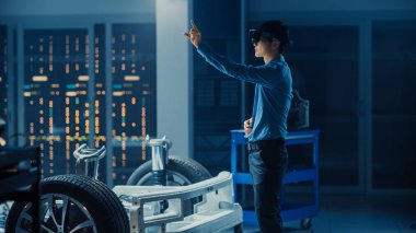 Elektrikli Oto Şasi PlatformuNda Çalışan Otomotiv Mühendisi, Dokunaklı Hareketlerle Artırılmış Gerçeklik Kulaklığı Kullanıyor. İnovasyon Laboratuvarı Nda Tesis Konsept Araç Çerçevesi Tekerlekli.