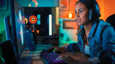 Kulaklık Pretty ve Heyecanlı Siyah Blogger Girl Onun Bilgisayarda First-Person Shooter Online Video Oyunu Oynuyor. Oda ve Pc Renkli Neon Led Işıklar var. Evde Rahat Akşam.