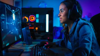 Kulaklık Pretty ve Heyecanlı Black Gamer Girl Onun Bilgisayarda First-Person Shooter Online Video Oyunu Oynuyor. Oda ve Pc Renkli Neon Led Işıklar var. Evde Rahat Akşam.