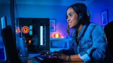 Kulaklık Pretty ve Heyecanlı Black Gamer Girl Onun Bilgisayarda First-Person Shooter Online Video Oyunu Oynuyor. Oda ve Pc Renkli Neon Led Işıklar var. Evde Rahat Akşam.