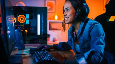 Kulaklık Pretty ve Heyecanlı Black Gamer Girl Onun Bilgisayarda First-Person Shooter Online Video Oyunu Oynuyor. Oda ve Pc Renkli Neon Led Işıklar var. Evde Rahat Akşam.