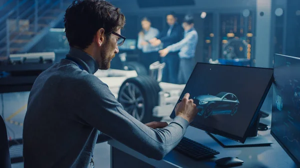 Designer gráfico automotivo profissional está trabalhando na renderização de carro conceito com uma caneta Stylus em um laboratório inovador de alta tecnologia com um chassi de carro protótipo . — Fotografia de Stock