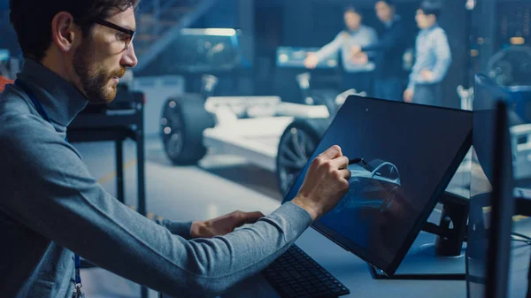 Professionele Automotive Graphic Designer werkt aan concept auto render met een stylus pen in een hightech innovatief laboratorium met een prototype auto chassis. — Stockfoto