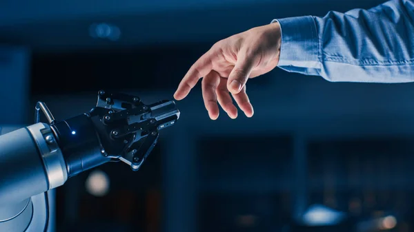 未来的なロボットアームは、人類と人工知能の統一ジェスチャーで人間の手に触れます。意識的な技術は人類と出会う。ミケランジェロのアダムの創造に触発されたコンセプト — ストック写真